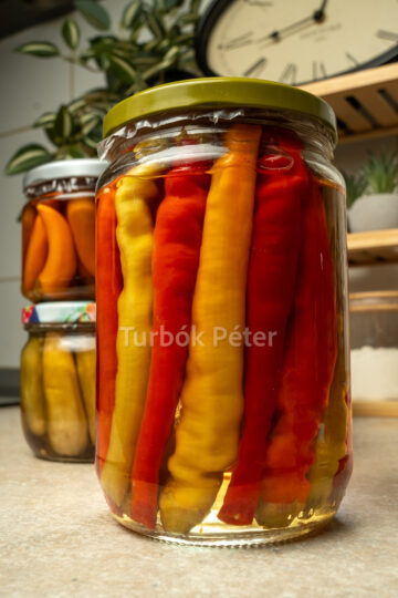 Sárga, narancssárga és piros pepperóni paprika egészben, tiszta ecetes felöntőlében eltéve